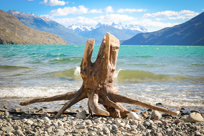 Uso de superposición para crear profundidad en fotografía de paisaje: tronco superpuesto en playa de lago de la Patagonia argentina