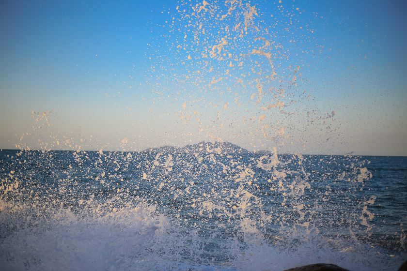 Uso de superposición de elementos para generar profundidad en fotografía de paisaje: ola rompiendo en mar de brasil con mar, morro y cielo de fondo